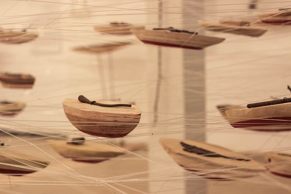 סירות עץ תלויות בין חוטי ניילון שקופים