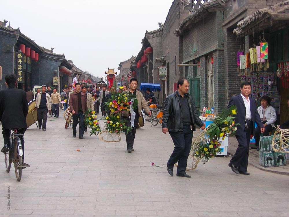 אנשים צועדים עם זרי פרחים