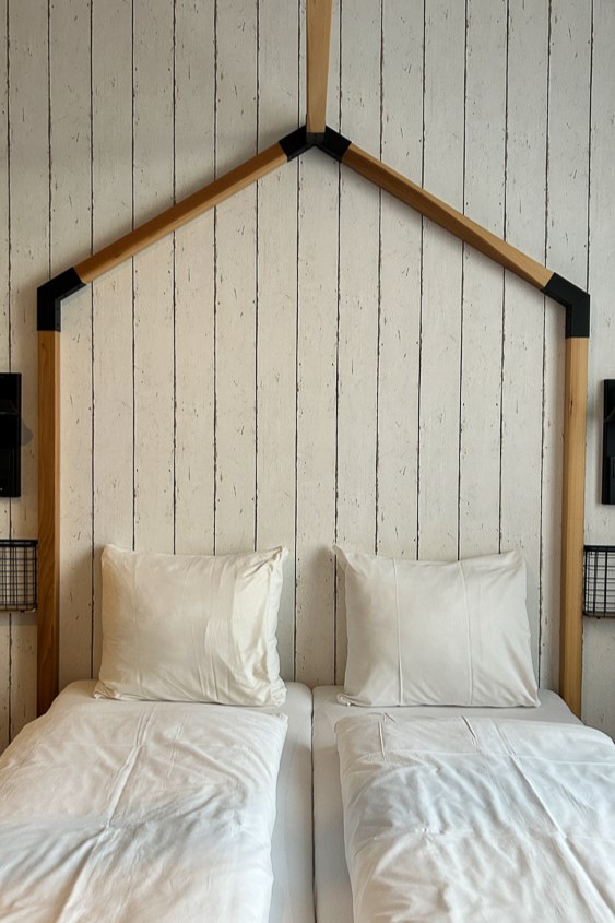 מיטה במלון על רקע קיר עץ לבן